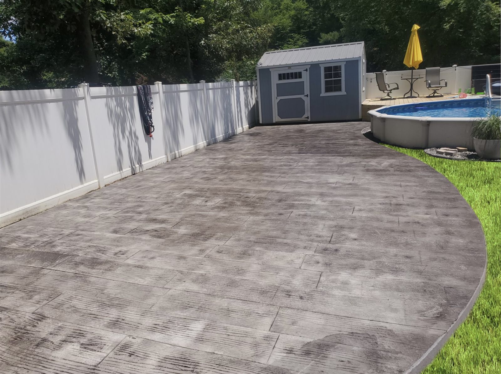 Curved stamped-concrete pool patio with wood-plank finish
